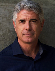 A middle-aged man with salt-and-pepper hair and a dark blue button-down shirt looking at the camera.