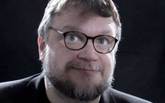 A man with short brown hair, glasses, and a salt-and-pepper beard looking forward against a dark background.