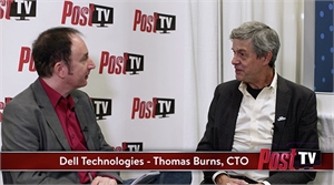 Two men sit facing each other in an interview setting against a branded backdrop.