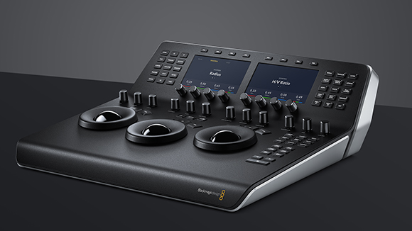 A black video editing console featuring three large trackballs, various knobs, and two digital display screens.