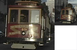 A red and gold vintage cable car traveling on a sloped city street.