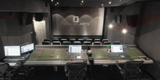 A dark sound mixing studio featuring two large mixing consoles and a screen reading Digital Arts.