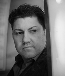 Black and white close-up portrait of a man looking off-camera with a serious expression.