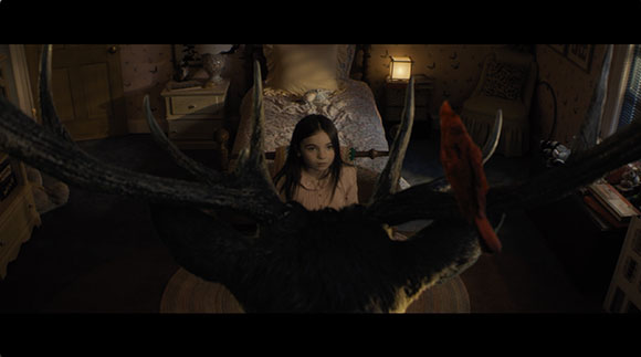 A person's face framed by large, dark antlers in a dimly lit room.