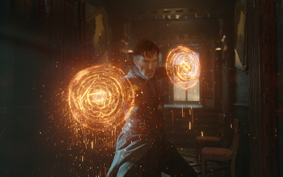 A man stands in a dark room holding two glowing, circular orange magical shields.
