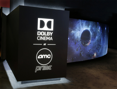 Black pedestal with white Dolby Cinema and AMC Prime logos next to a large curved screen showing a cosmic scene.