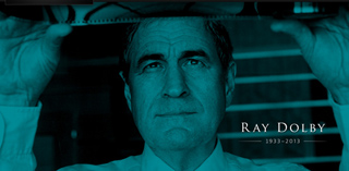 A blue-toned portrait of Ray Dolby holding a strip of film up to the light.