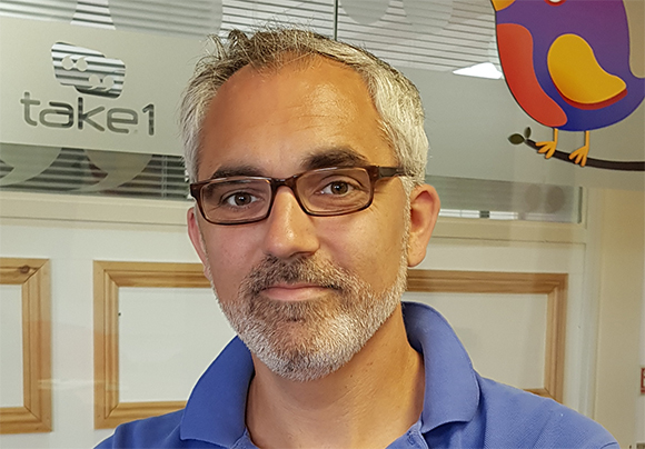 A man with short graying hair and glasses wearing a blue polo shirt.