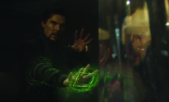 A man reaches toward a reflective surface with glowing green magical energy swirling around his hand.
