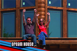 A man and a woman in sunglasses sit on a wooden ledge with their arms raised in celebration.