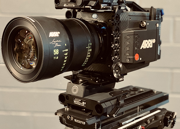 A black ARRI cinema camera with a large Signature Prime lens mounted on a professional tripod.