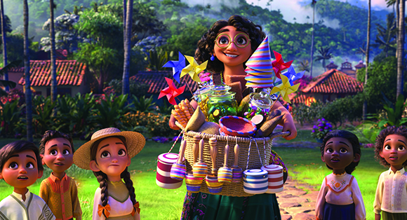 A smiling woman with glasses carries a large basket filled with toys and treats toward four children.