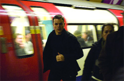 A man in a black jacket walks past a red and white subway train in a station.