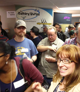 A crowd of people socializing indoors near a sign for The Editors' Lounge and an Avid logo.