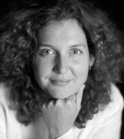 Black and white portrait of a woman with voluminous curly hair resting her chin on her hand.