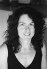 Black and white portrait of a smiling woman with dark, curly hair wearing a dark tank top.