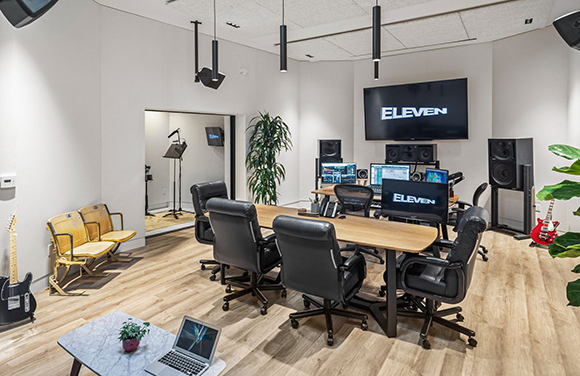 A professional recording studio with mixing consoles, monitors, studio chairs, and acoustic treatment.