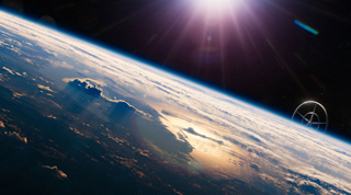 A view of Earth's curved horizon from space with bright sunlight and lens flares.