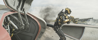 A black and gold humanoid robot stands in a smoky, desolate landscape near a metallic structure.