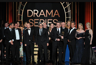 A group of people in formal attire standing on a stage in front of a large sign that reads DRAMA SERIES.