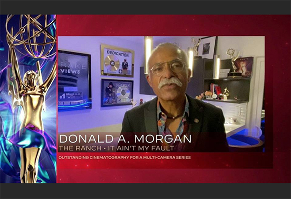 Donald A. Morgan speaks in front of a background featuring framed awards and a gold Emmy statue.