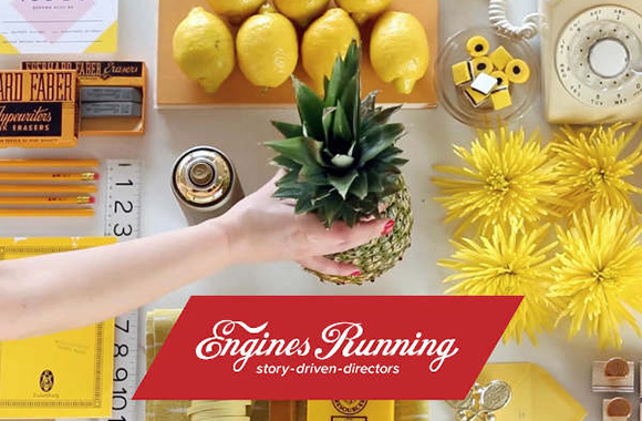 Top-down view of lemons, a pineapple, yellow flowers, a vintage telephone, and pencils on a white surface.