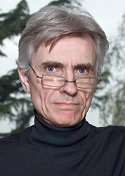 A man with grey hair and glasses wearing a black turtleneck.