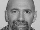 Black and white close-up portrait of a man with a shaved head and a goatee.