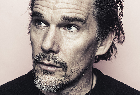 Close-up portrait of a man with graying hair and a beard looking up and to the side.