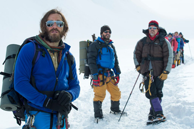 A group of hikers in colorful winter clothing and backpacks standing in a snowy landscape.