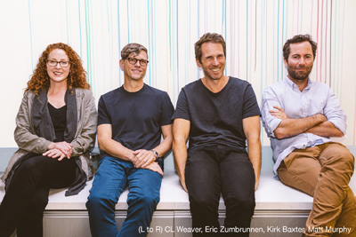 Four people sit side-by-side on a white bench against a background of vertical pastel stripes.