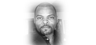 Black and white headshot of a man with a short beard and mustache looking forward.