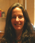 A smiling woman with long, dark brown hair looking toward the camera.