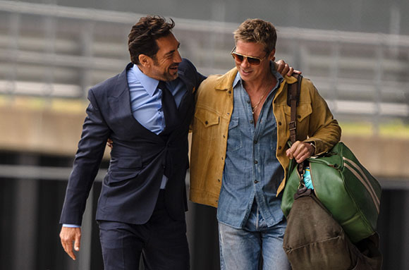 Two men smiling and walking side-by-side with arms around each other's shoulders.