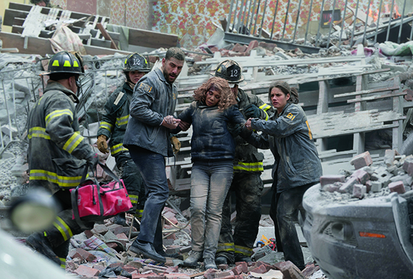 Rescuers carry a woman through debris at a collapsed building site.