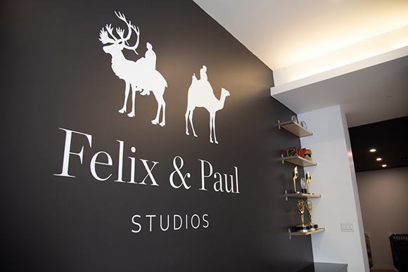White logo of a person riding a reindeer and a person riding a camel above the text Felix & Paul Studios.