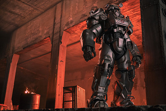 A heavy, metallic armored suit stands in a dark, red-lit industrial structure.