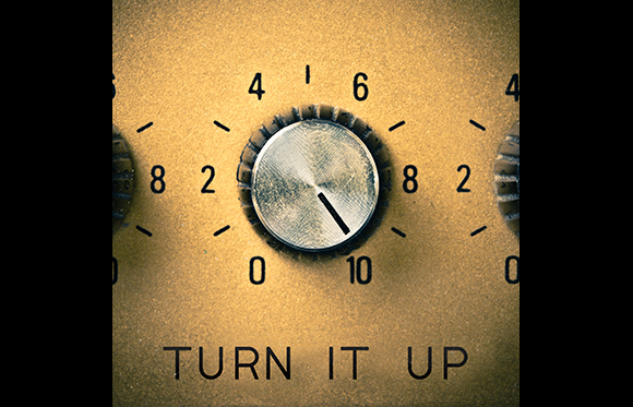 A silver metallic control knob on a gold-toned panel with numbers and the text TURN IT UP.