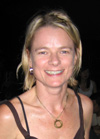 A smiling blonde woman wearing a dark tank top and a gold necklace.