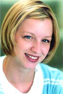 A smiling woman with short blonde hair wearing a light blue and white shirt.