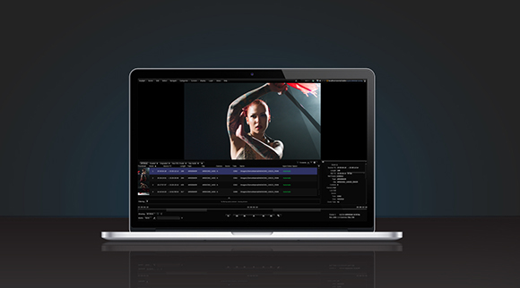 A laptop on a dark surface showing a video editing interface with a clip of a person holding a sword.