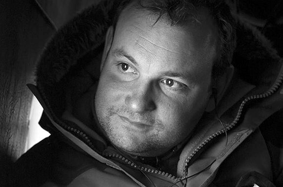 Black and white close-up of a man looking off-camera while wearing a heavy hooded jacket.