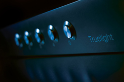 Close-up of a dark control panel with five glowing blue circular buttons and the word Truelight.