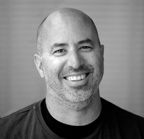 A smiling bald man with light facial hair looking toward the camera.