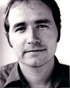 Black and white close-up portrait of a man looking toward the camera.