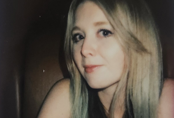A close-up portrait of a woman with long blonde hair looking slightly off-center.