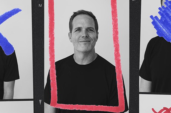 Black and white portrait of a smiling man in a black t-shirt inside a red hand-drawn frame.