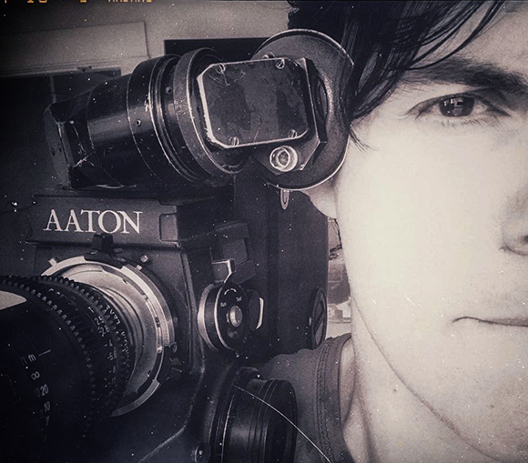 A close-up of a person's face next to a professional Aaton motion picture camera.