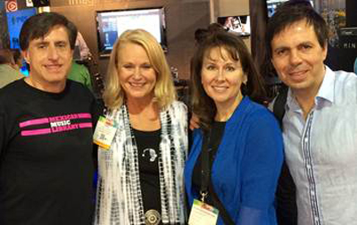 Four smiling adults standing together in a group photo indoors.
