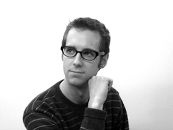 Black and white portrait of a man with glasses looking off to the side with his hand near his chin.